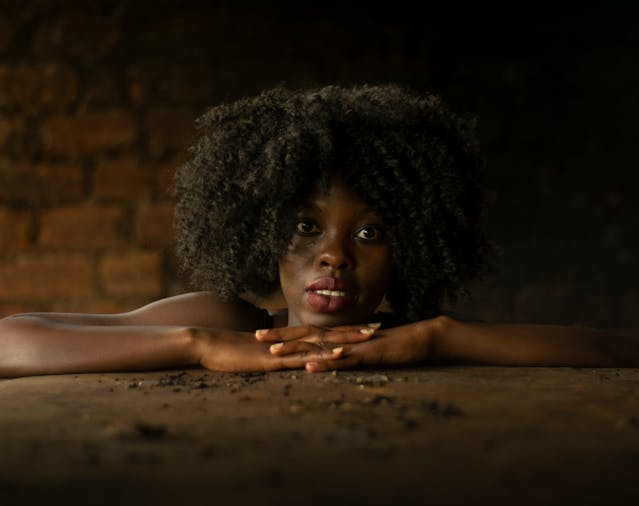 A imagem mostra uma jovem negra com seu cabelo volumoso tipo c, a imagem retrata o tema "Rotina Capilar para Cachos Definidos e Saudáveis"