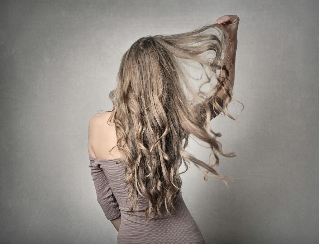 Mulher de costas com um lindo cabelo ondulado solto , onde representa o tema cabelos ondulados
