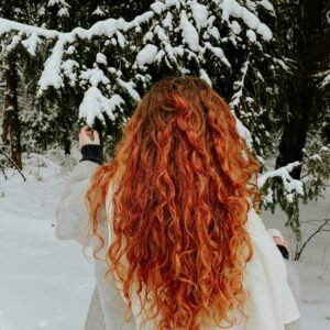 A imagem mostra uma mulher de costas com um cabelo solto ondulado vermelho, representando o tema " cabelos ondulados"