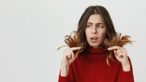Mulher olhando para as pontas do seu cabelo.Descubra tudo sobre Porosidade Capilar